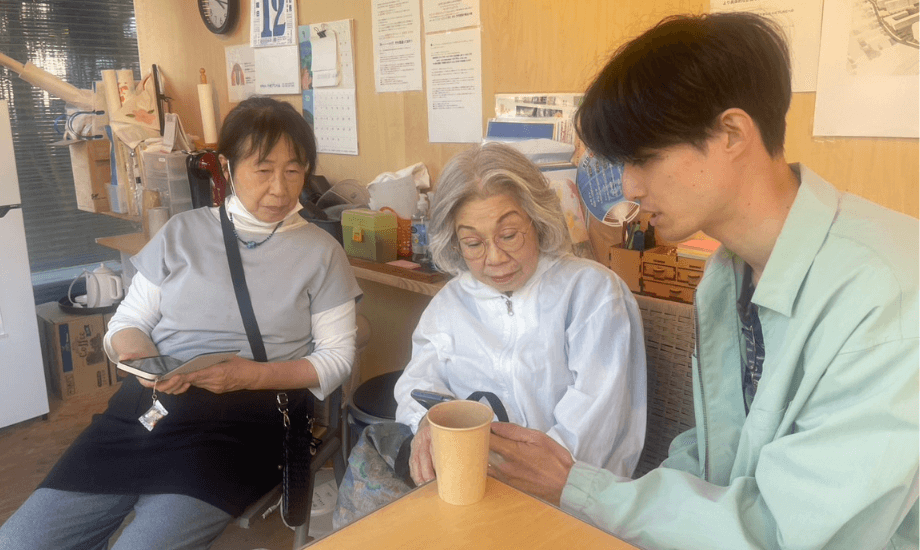 団地コミュニティでのスマホ教室にて。スマホ操作を教えている服部さん(写真右)。