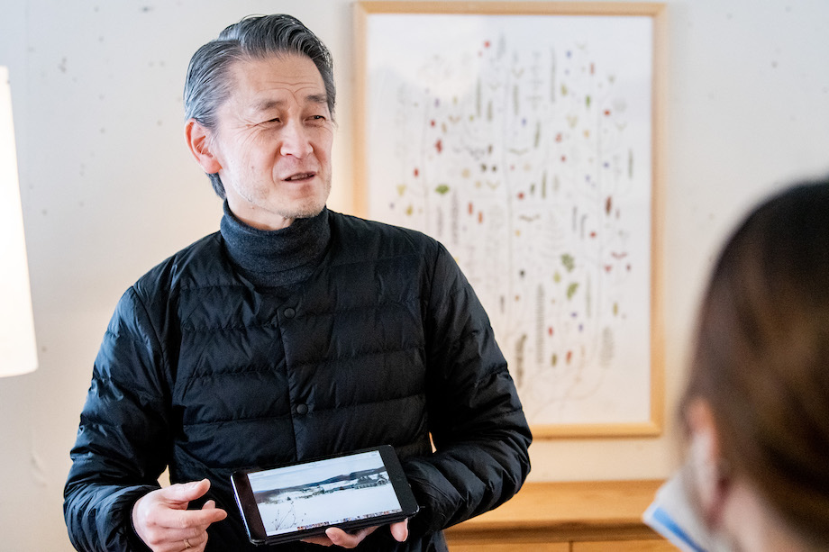 秦野 誠治 （Hatano Seiji) さん / 「北の住まい設計社」で建築・設計から営業まで幅広い業務を行う。北海道旭川市出身。旭川で建築事務所での勤務を経て2000年～現在の会社へ。「北の住まい設計社」代表渡辺さんの想いである、自然に還るモノづくりを実現するために日々努力を惜しまない。取材当日に見せてくれたタブレットには、木がほとんどない当時の敷地の写真が映る。