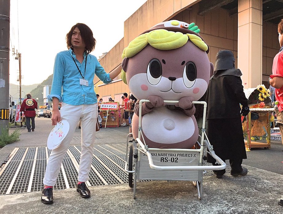 写真左:守時 健 氏、右:高知県須崎市公式マスコットキャラクター「しんじょう君」/ 1986年生まれ。岡山県倉敷市出身。高校時代はバンド活動と読書に明け暮れ、卒業後は愛知県豊田市で自動車メーカーの期間工として働いたり、大阪市でフリーター生活を送ったのち、大学へ入学。大学時代に訪れた高知県須崎市を気に入り、そのまま須崎市役所へ就職を決める。須崎市のマスコットキャラクター担当に自ら名乗りをあげ、その後「ゆるキャラ」と「ふるさと納税」を掛け合わせた事業で、2014年度には200万円だった市の納税額を16年度には10億円近くまで増やした。