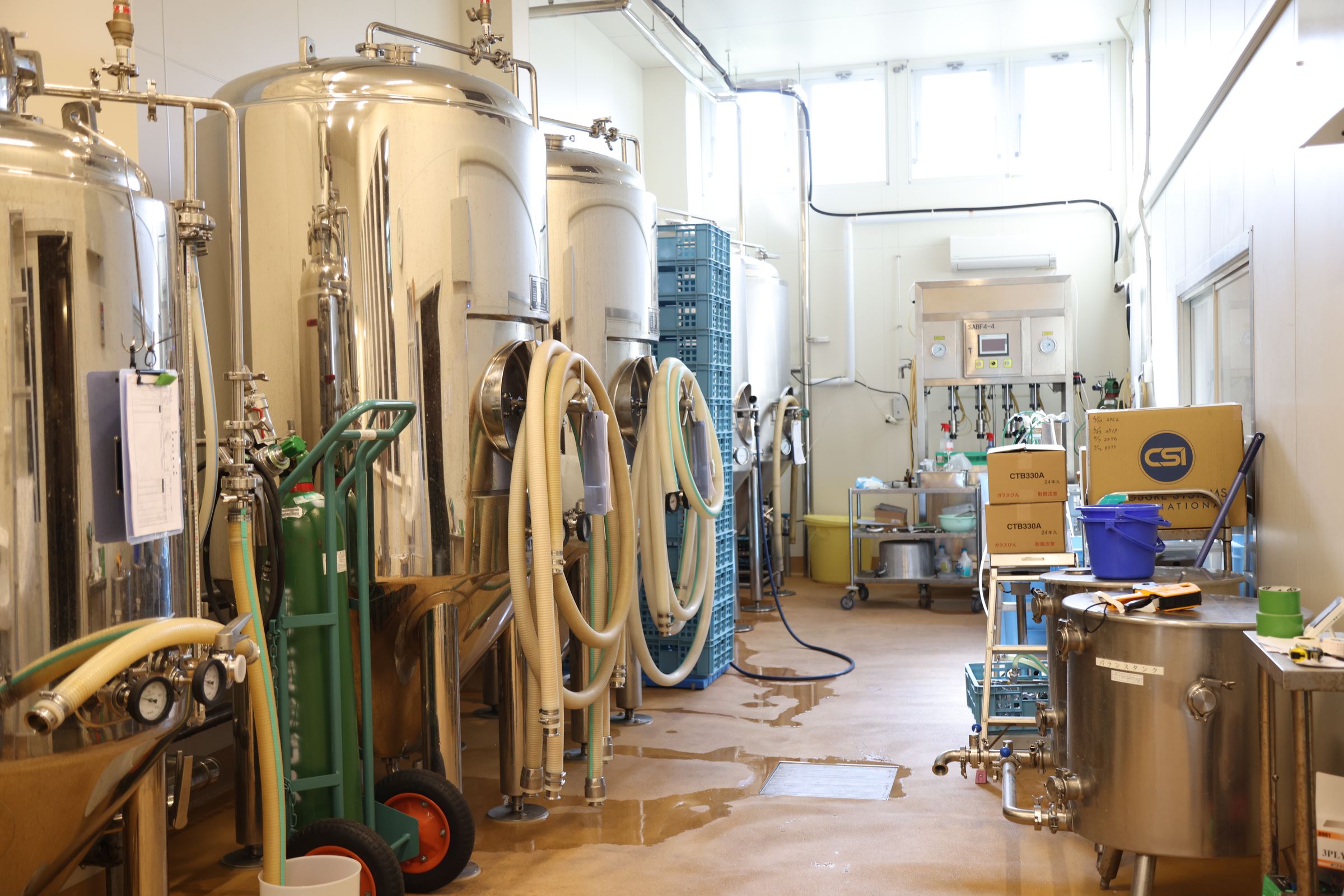 作業場のようす。左手前の発酵タンクでビールを発酵させ、完成したらケグ樽に移して冷蔵庫で保管。在庫を見ながら適正な本数を見極めつつ右奥の瓶詰め機械で瓶に充填し、出荷となる。