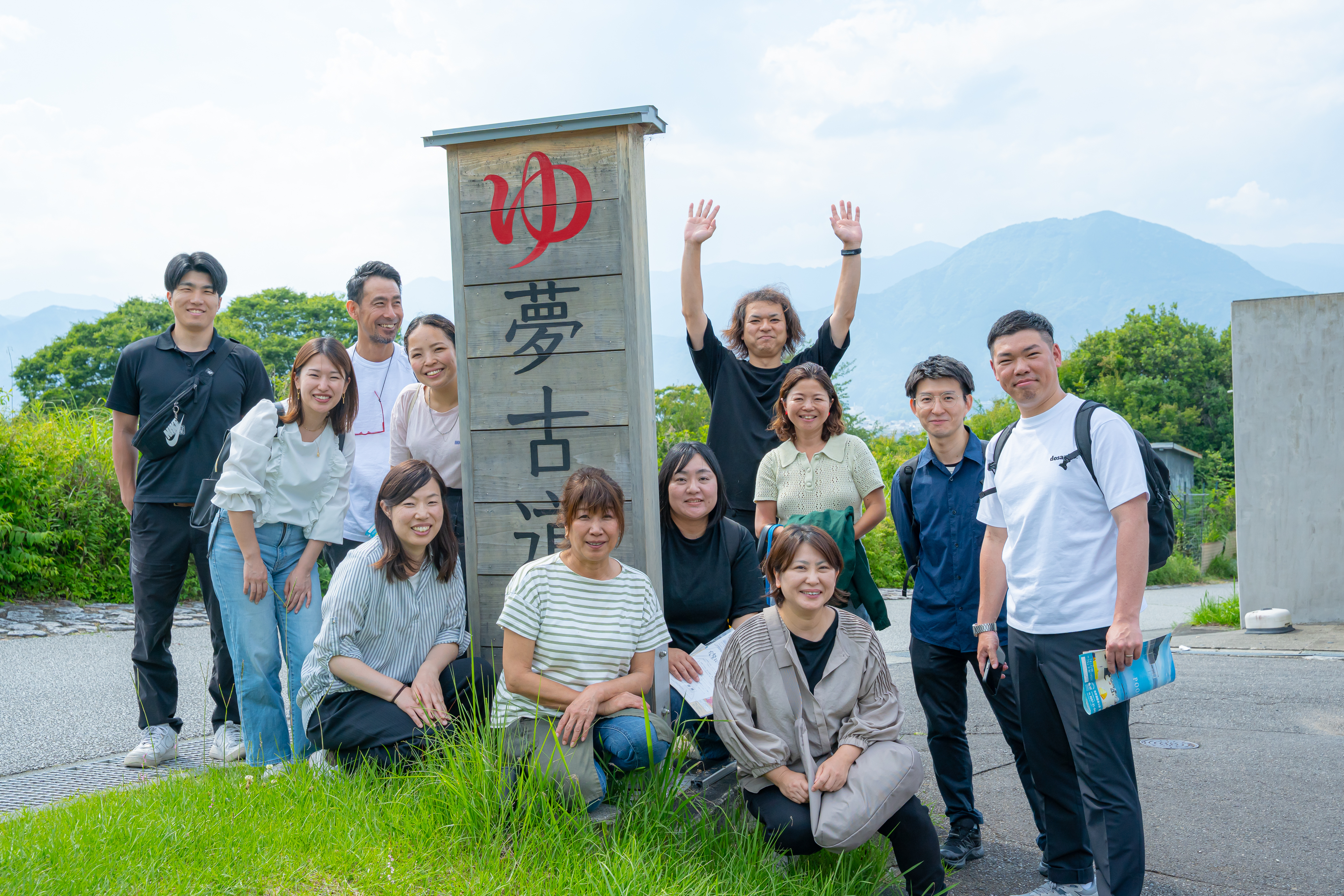 「夢古道」の看板前で記念撮影する地域バイヤープログラム受講生とスタッフの集合写真